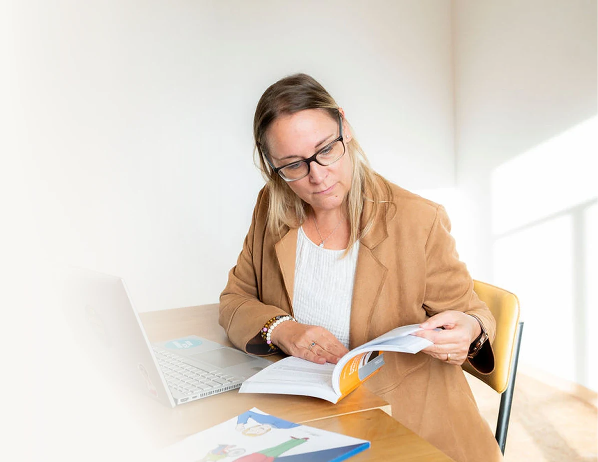 Frau liest Fachbuch bei Beratungssitzung in hellem Büro.