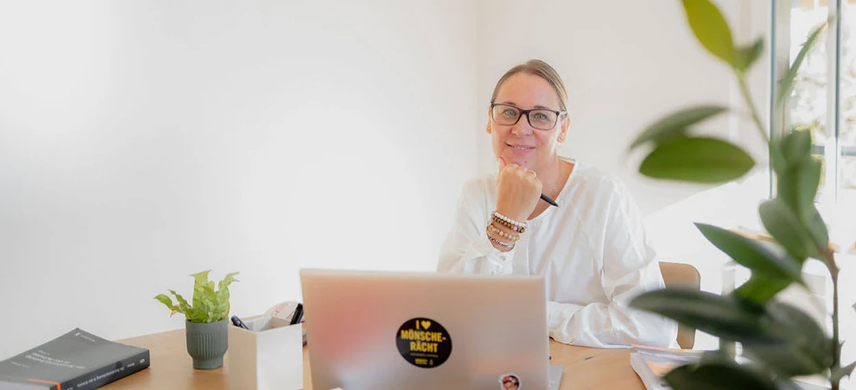 Frau bei Sydefin in Beratungssituation mit Laptop und Pflanzen.